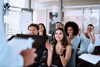 Diverse group of smiling professionals clapping enthusiastically during an inspiring presentation at Verbossa